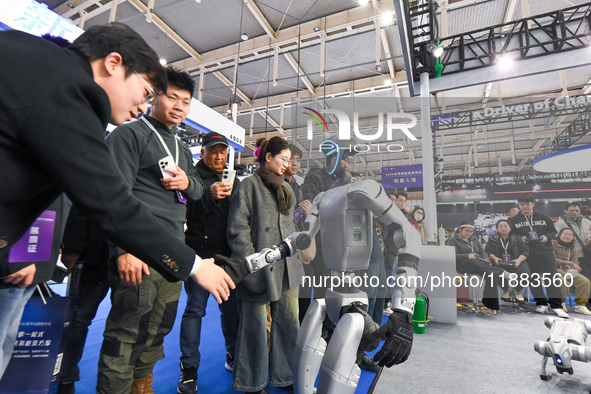 People shake hands with humanoid robots at the 2024 World Intelligent Manufacturing Conference in Nanjing, China, on December 20, 2024. 