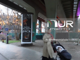 A woman pushes a baby stroller under a bridge in Munich, Bavaria, Germany, on December 18, 2024. The scene includes urban infrastructure, a...