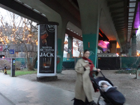 A woman pushes a baby stroller under a bridge in Munich, Bavaria, Germany, on December 18, 2024. The scene includes urban infrastructure, a...