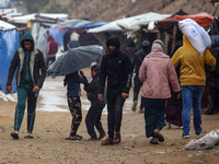 Displaced Palestinians walk in the rain at a makeshift camp in Khan Yunis, Gaza Strip, on December 20, 2024, amid the ongoing war between Is...