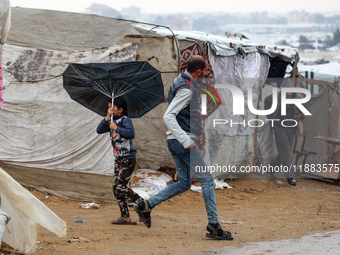 Displaced Palestinians walk in the rain at a makeshift camp in Khan Yunis, Gaza Strip, on December 20, 2024, amid the ongoing war between Is...