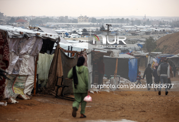 Displaced Palestinians walk in the rain at a makeshift camp in Khan Yunis, Gaza Strip, on December 20, 2024, amid the ongoing war between Is...