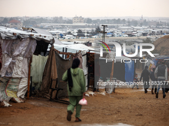 Displaced Palestinians walk in the rain at a makeshift camp in Khan Yunis, Gaza Strip, on December 20, 2024, amid the ongoing war between Is...