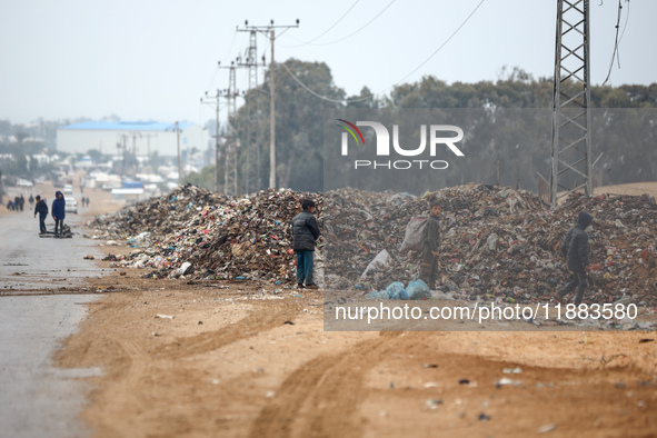 Palestinian boys search for salvageable items to reuse amid a pile of garbage in the war-battered city of Khan Yunis in the southern Gaza St...