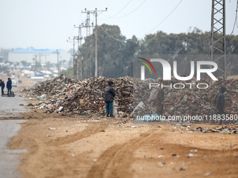 Palestinian boys search for salvageable items to reuse amid a pile of garbage in the war-battered city of Khan Yunis in the southern Gaza St...