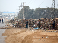 Palestinian boys search for salvageable items to reuse amid a pile of garbage in the war-battered city of Khan Yunis in the southern Gaza St...