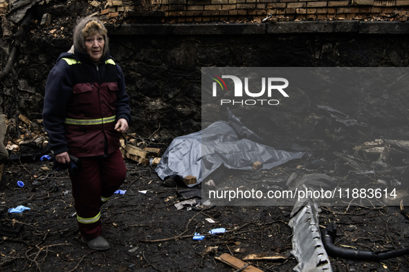 Communal workers clean the street as the body of a person killed in a Russian missile strike lies nearby in central Kyiv, Ukraine, on Decemb...