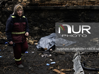 Communal workers clean the street as the body of a person killed in a Russian missile strike lies nearby in central Kyiv, Ukraine, on Decemb...