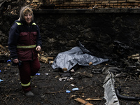 Communal workers clean the street as the body of a person killed in a Russian missile strike lies nearby in central Kyiv, Ukraine, on Decemb...