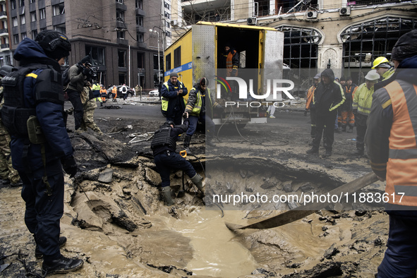 Experts examine a crater caused by a Russian missile strike in central Kyiv, Ukraine, on December 20, 2024. 