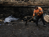 Communal workers clean the street as the body of a person killed in a Russian missile strike lies nearby in central Kyiv, Ukraine, on Decemb...