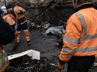 Communal workers clean the street as the body of a person killed in a Russian missile strike lies nearby in central Kyiv, Ukraine, on Decemb...