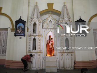 A woman cleans a statue inside a church in Kolkata, India, on December 20, 2024, ahead of Christmas celebrations. (