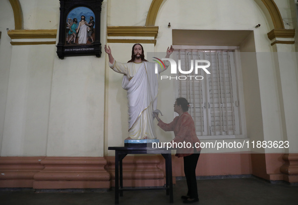 A woman cleans a statue of Jesus Christ inside a church in Kolkata, India, on December 20, 2024, ahead of Christmas celebrations. 