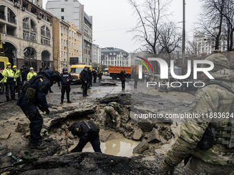 Experts examine a crater caused by a Russian missile strike in central Kyiv, Ukraine, on December 20, 2024. (