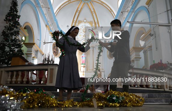 A nun and a worker decorate a church ahead of Christmas celebrations in Kolkata, India, on December 20, 2024. 