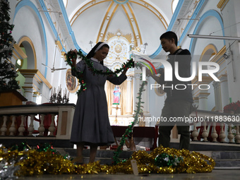 A nun and a worker decorate a church ahead of Christmas celebrations in Kolkata, India, on December 20, 2024. (