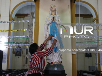 A woman cleans a statue inside a church in Kolkata, India, on December 20, 2024, ahead of Christmas celebrations. (