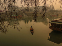 A man rows a boat on the waters of the Jhelum River in Srinagar, Jammu and Kashmir, on December 20, 2024. Kashmir remains in the grip of a c...