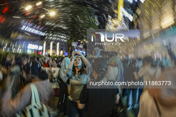 Visitors celebrate after artificial snow fills the Christmas decoration outside a shopping mall in Kuala Lumpur, Malaysia, on December 19, 2...