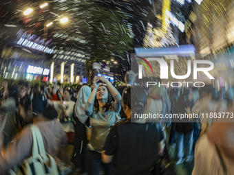 Visitors celebrate after artificial snow fills the Christmas decoration outside a shopping mall in Kuala Lumpur, Malaysia, on December 19, 2...