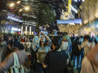 Visitors celebrate after artificial snow fills the Christmas decoration outside a shopping mall in Kuala Lumpur, Malaysia, on December 19, 2...