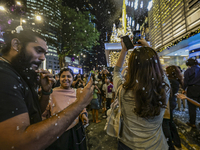 Visitors celebrate after artificial snow fills the Christmas decoration outside a shopping mall in Kuala Lumpur, Malaysia, on December 19, 2...