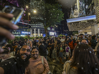 Visitors celebrate after artificial snow fills the Christmas decoration outside a shopping mall in Kuala Lumpur, Malaysia, on December 19, 2...