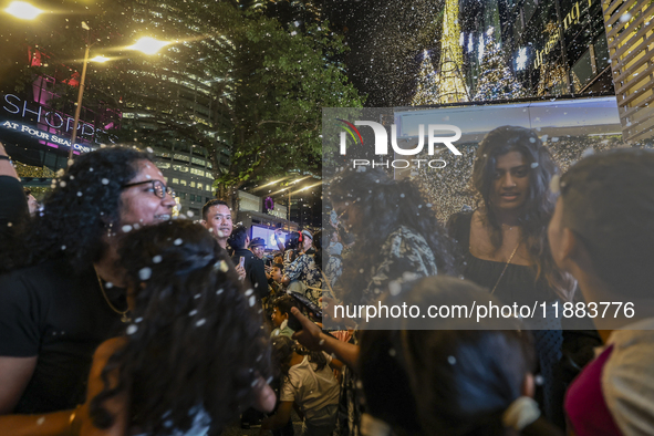 Visitors celebrate after artificial snow fills the Christmas decoration outside a shopping mall in Kuala Lumpur, Malaysia, on December 19, 2...