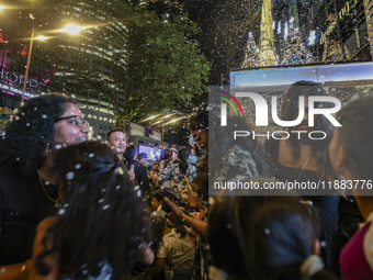 Visitors celebrate after artificial snow fills the Christmas decoration outside a shopping mall in Kuala Lumpur, Malaysia, on December 19, 2...