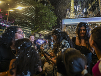 Visitors celebrate after artificial snow fills the Christmas decoration outside a shopping mall in Kuala Lumpur, Malaysia, on December 19, 2...