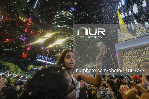 Visitors celebrate after artificial snow fills the Christmas decoration outside a shopping mall in Kuala Lumpur, Malaysia, on December 19, 2...