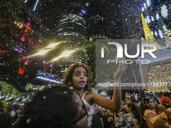 Visitors celebrate after artificial snow fills the Christmas decoration outside a shopping mall in Kuala Lumpur, Malaysia, on December 19, 2...