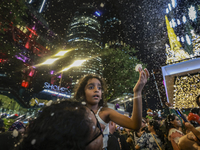 Visitors celebrate after artificial snow fills the Christmas decoration outside a shopping mall in Kuala Lumpur, Malaysia, on December 19, 2...