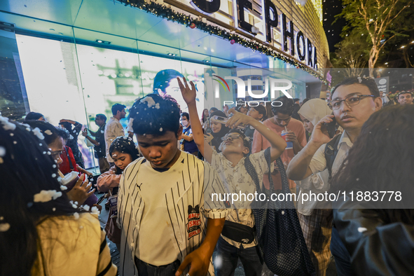 Visitors celebrate after artificial snow fills the Christmas decoration outside a shopping mall in Kuala Lumpur, Malaysia, on December 19, 2...