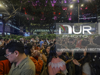 Visitors celebrate after artificial snow fills the Christmas decoration outside a shopping mall in Kuala Lumpur, Malaysia, on December 19, 2...