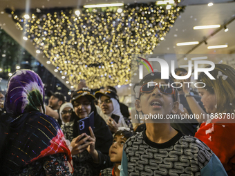 Visitors celebrate after artificial snow fills the Christmas decoration outside a shopping mall in Kuala Lumpur, Malaysia, on December 19, 2...