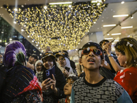 Visitors celebrate after artificial snow fills the Christmas decoration outside a shopping mall in Kuala Lumpur, Malaysia, on December 19, 2...