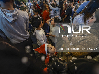 Visitors celebrate after artificial snow fills the Christmas decoration outside a shopping mall in Kuala Lumpur, Malaysia, on December 19, 2...