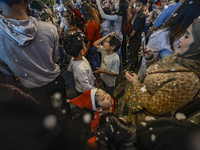 Visitors celebrate after artificial snow fills the Christmas decoration outside a shopping mall in Kuala Lumpur, Malaysia, on December 19, 2...