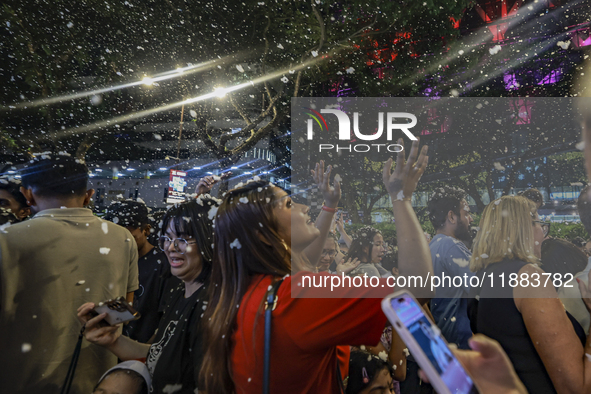 Visitors celebrate after artificial snow fills the Christmas decoration outside a shopping mall in Kuala Lumpur, Malaysia, on December 19, 2...