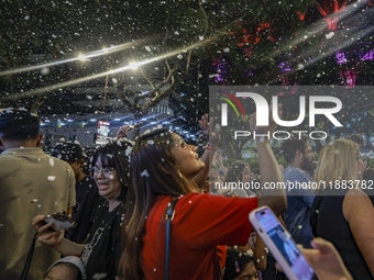 Visitors celebrate after artificial snow fills the Christmas decoration outside a shopping mall in Kuala Lumpur, Malaysia, on December 19, 2...