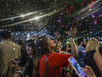 Visitors celebrate after artificial snow fills the Christmas decoration outside a shopping mall in Kuala Lumpur, Malaysia, on December 19, 2...