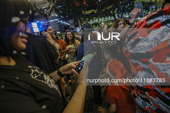 Visitors celebrate after artificial snow fills the Christmas decoration outside a shopping mall in Kuala Lumpur, Malaysia, on December 19, 2...