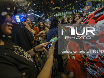 Visitors celebrate after artificial snow fills the Christmas decoration outside a shopping mall in Kuala Lumpur, Malaysia, on December 19, 2...