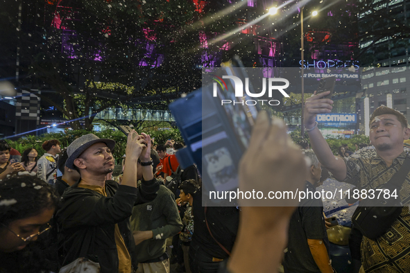 Visitors celebrate after artificial snow fills the Christmas decoration outside a shopping mall in Kuala Lumpur, Malaysia, on December 19, 2...