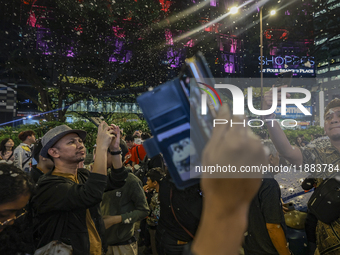 Visitors celebrate after artificial snow fills the Christmas decoration outside a shopping mall in Kuala Lumpur, Malaysia, on December 19, 2...