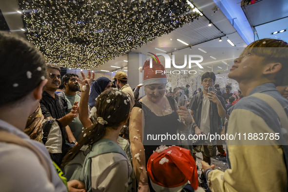 Visitors celebrate after artificial snow fills the Christmas decoration outside a shopping mall in Kuala Lumpur, Malaysia, on December 19, 2...