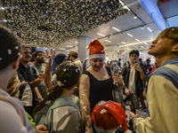 Visitors celebrate after artificial snow fills the Christmas decoration outside a shopping mall in Kuala Lumpur, Malaysia, on December 19, 2...