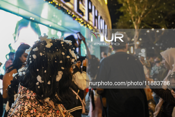 Visitors celebrate after artificial snow fills the Christmas decoration outside a shopping mall in Kuala Lumpur, Malaysia, on December 19, 2...